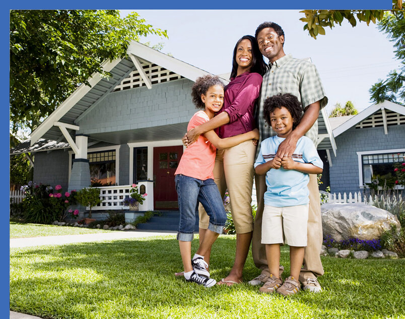 Family of 4 posing in front of their house that has home insurance